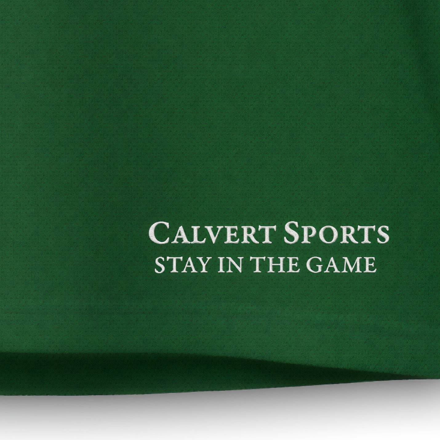 Gesticktes CALVERT SPORTS Schriftlogo mit Claim ‚Stay in the Game‘ in Weiß auf dem grünen Fan-Polo Deutschland 2026